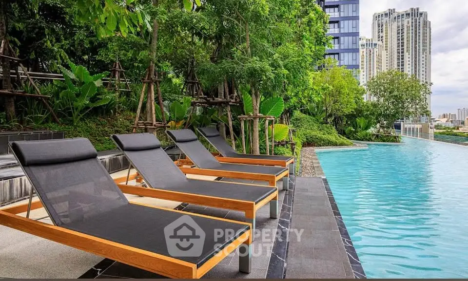 Luxurious poolside area with modern loungers and lush greenery in a high-rise residential complex.