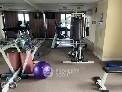 Spacious gym with modern equipment in a residential building, perfect for fitness enthusiasts.