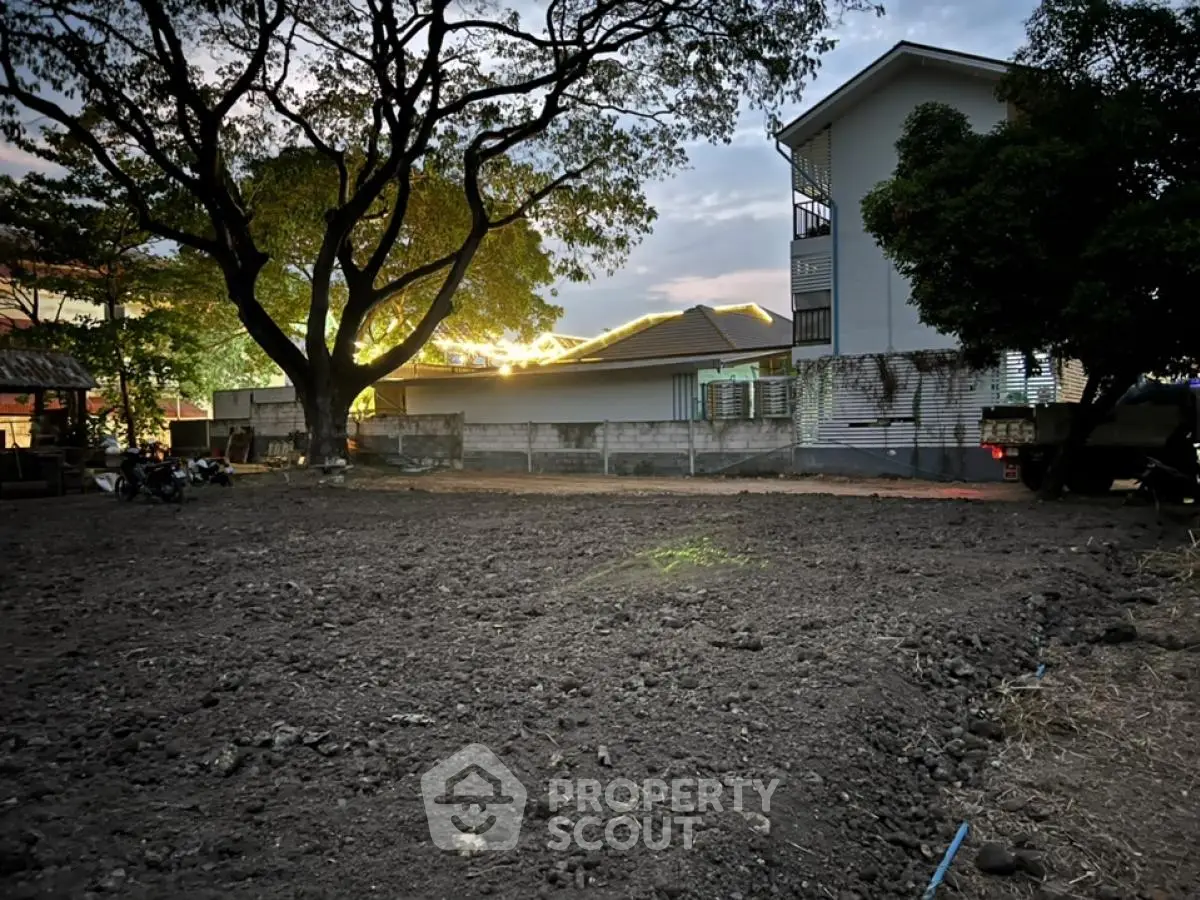 Spacious land plot with mature trees and residential building, perfect for development opportunities.
