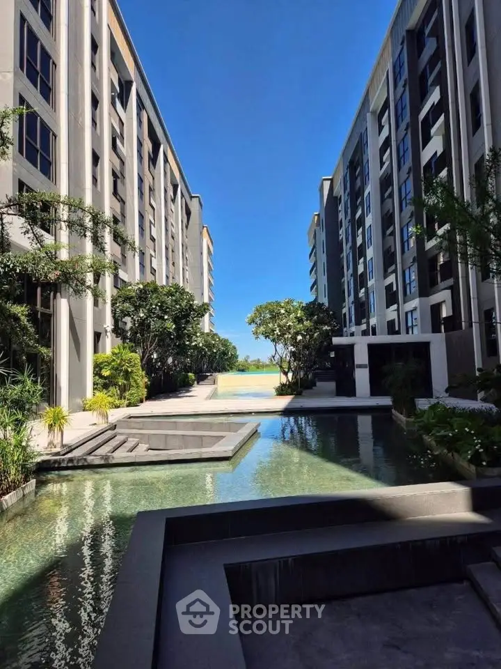 Luxurious modern apartment complex with serene water feature and lush greenery