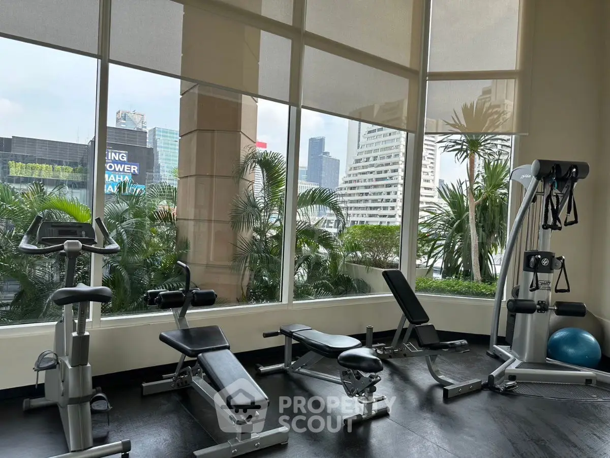 Spacious gym with modern equipment and city view, perfect for fitness enthusiasts.