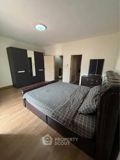 Spacious bedroom with elegant dark wood furniture and ample natural light.