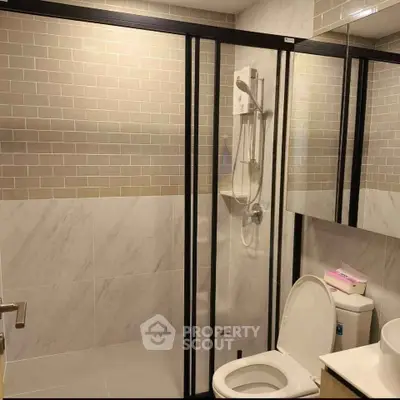 Modern bathroom with glass shower enclosure and sleek tile design.