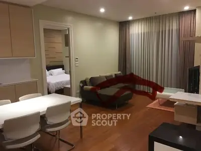 Modern open-plan living room with dining area and cozy bedroom view.