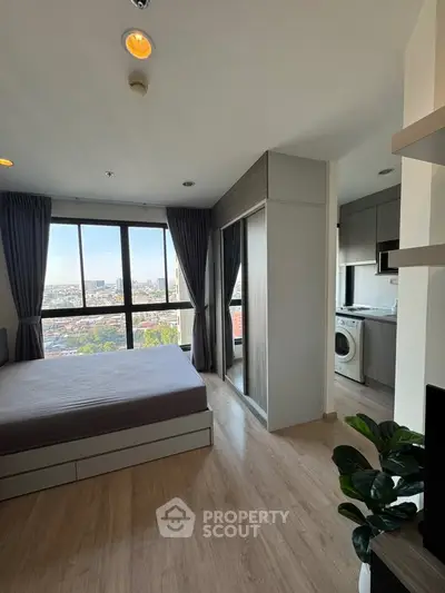 Modern bedroom with city view and adjacent kitchen area in a stylish apartment.