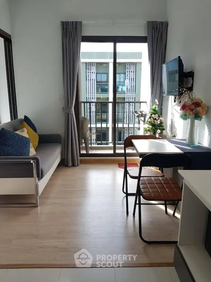 Modern living room with balcony view, stylish decor, and natural light in urban apartment.