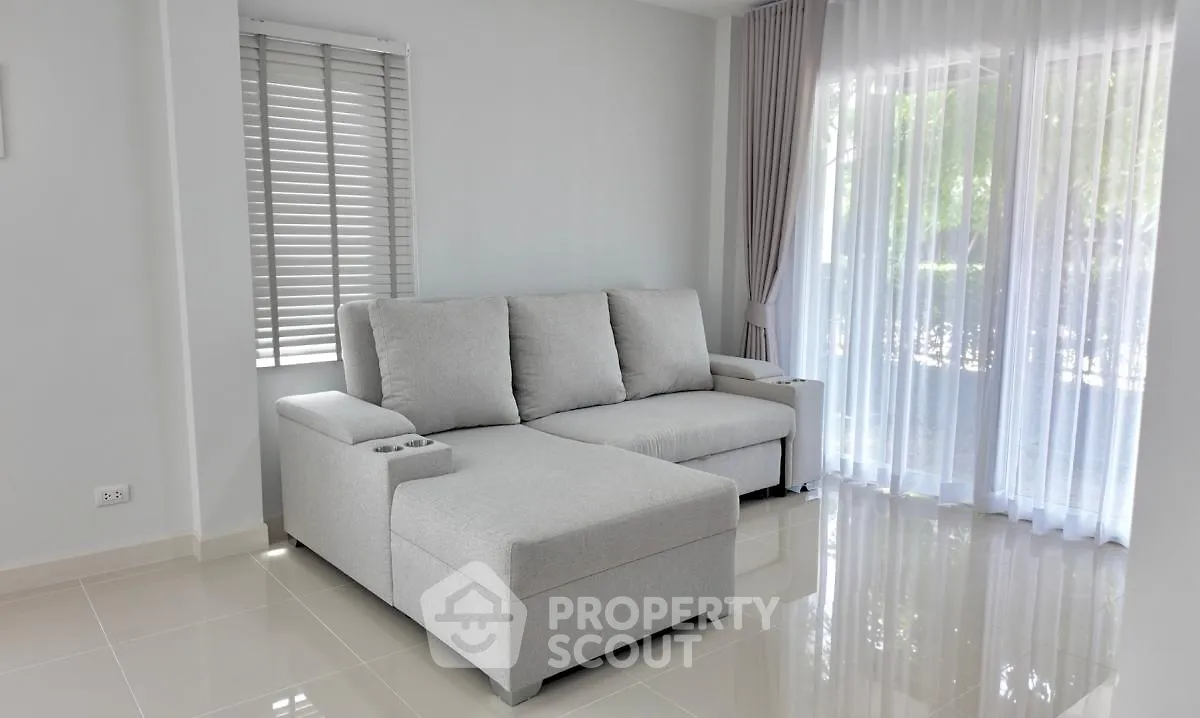 Bright and airy living room with modern gray sectional sofa and large windows with sheer curtains.