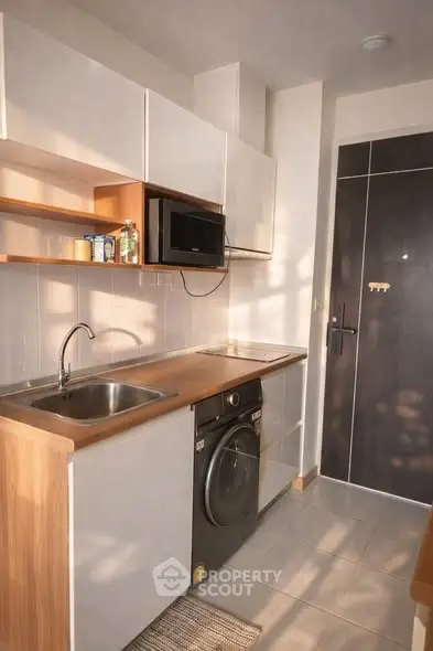 Modern compact kitchen with sleek cabinetry and integrated appliances in a cozy apartment.