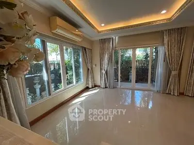 Spacious living room with large windows and elegant curtains, featuring modern lighting and air conditioning.