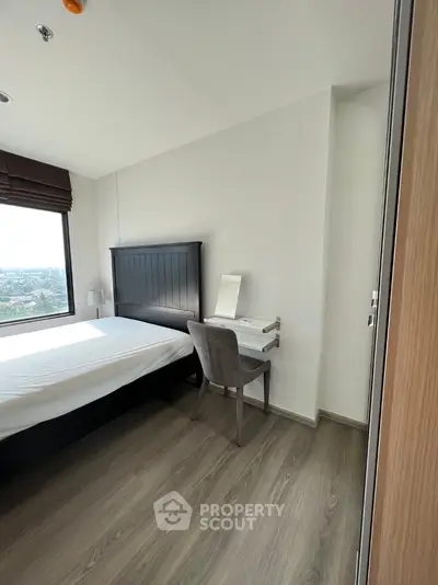 Modern bedroom with wooden flooring and large window offering scenic view
