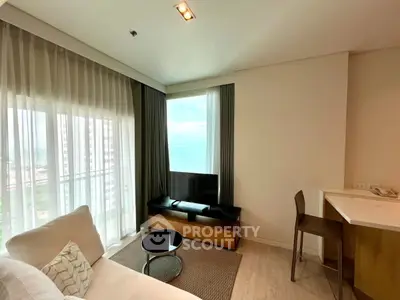 Modern living room with ocean view, featuring sleek furniture and large windows for natural light.