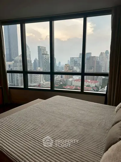Luxurious bedroom with stunning city skyline view from large windows.
