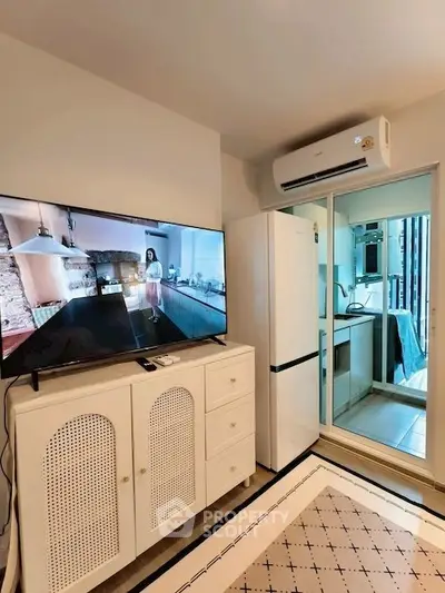 Modern living room with TV, air conditioning, and sleek kitchen appliances.