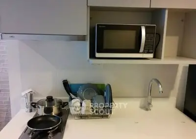 Modern kitchen with microwave, stove, and dish rack in sleek design.
