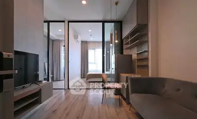 Modern living room with sleek design and open layout leading to a cozy bedroom.