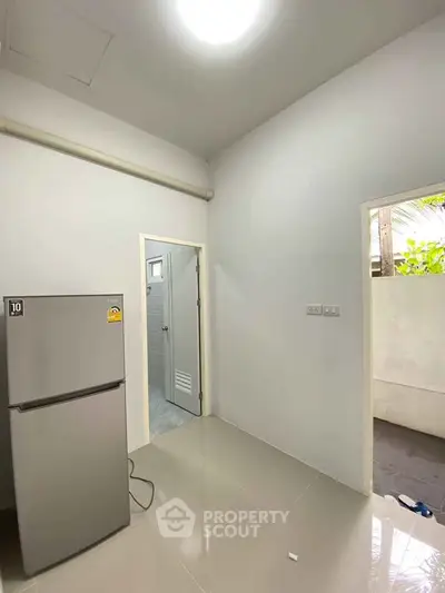 Minimalist kitchen area with modern fridge and tiled flooring