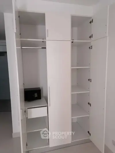 Spacious white wardrobe with multiple shelves and a safe, ideal for organized storage.