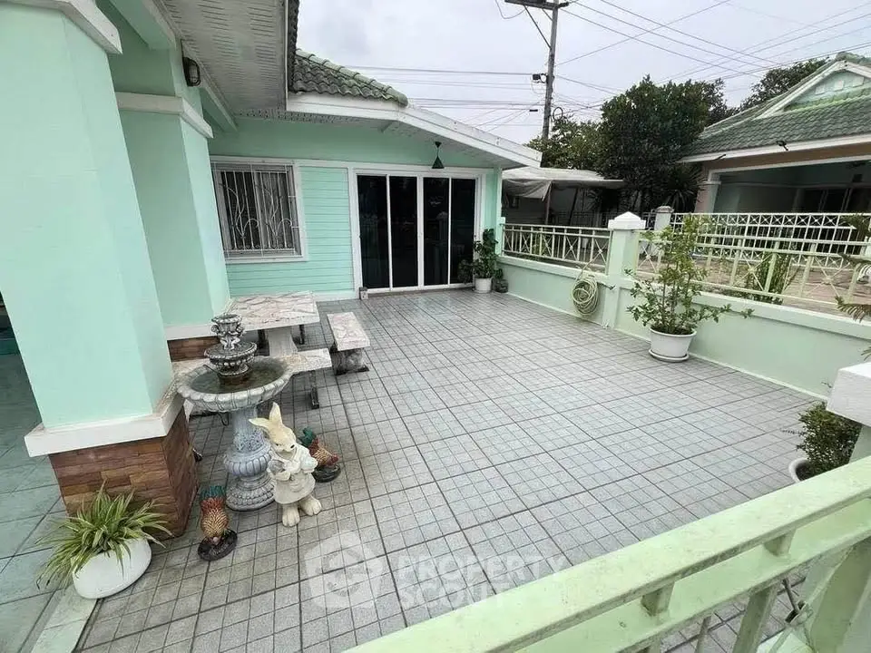 Charming mint green house with spacious tiled patio and decorative garden accents.