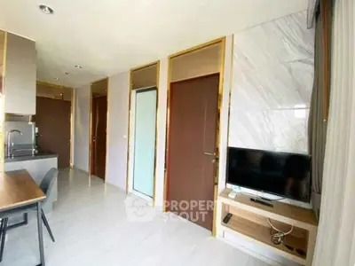 Modern apartment interior with sleek kitchen and cozy living area featuring a wall-mounted TV.