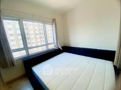 Bright bedroom with large window and modern bed in urban apartment.