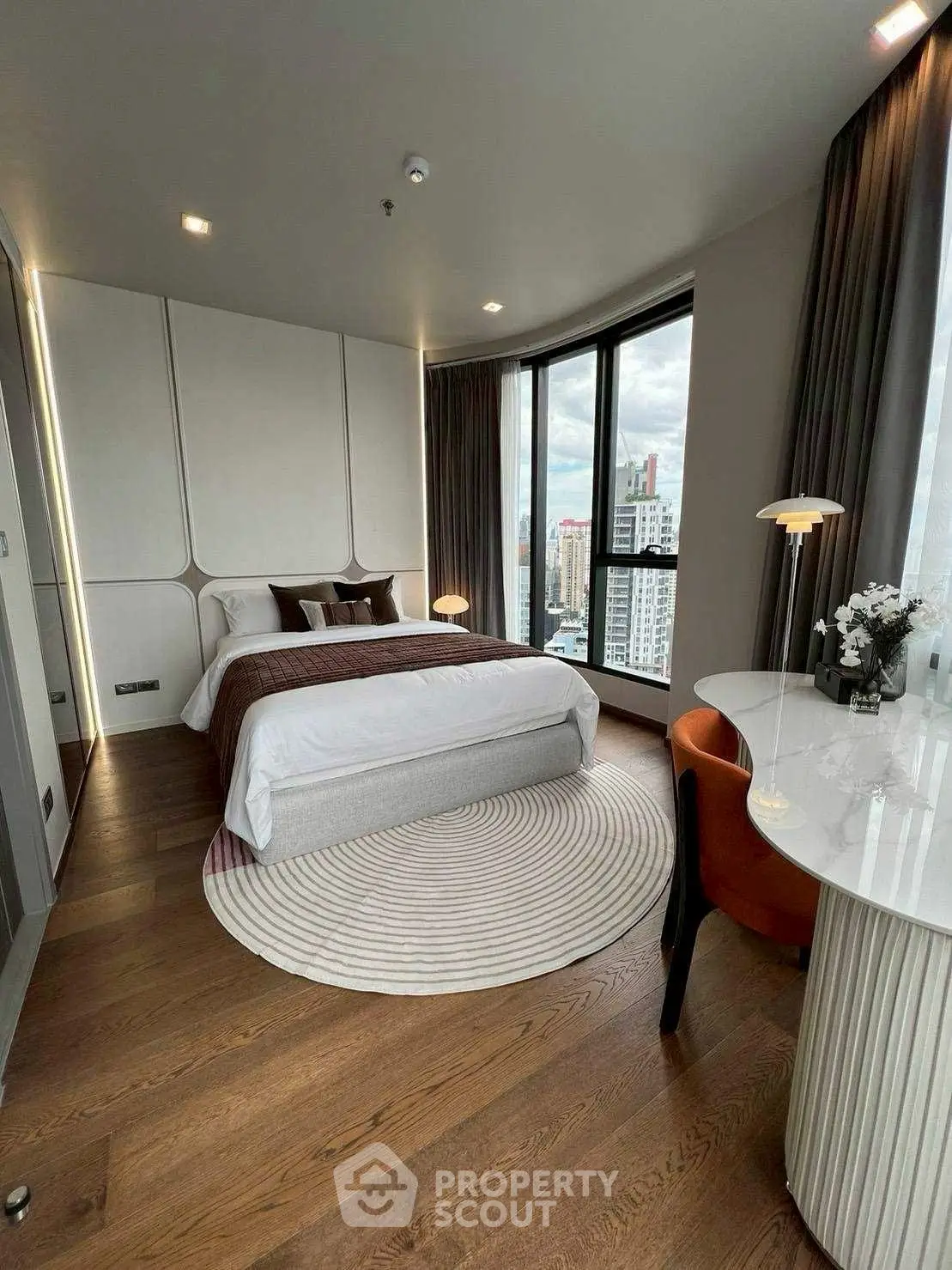 Luxurious bedroom with city view, modern decor, and elegant furnishings in high-rise apartment.