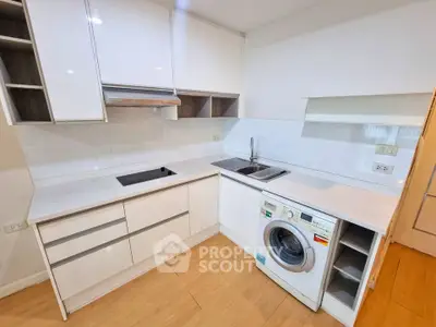 Modern kitchen with sleek white cabinetry and built-in washing machine