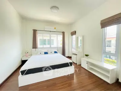 Spacious bedroom with modern furnishings and large windows offering natural light.