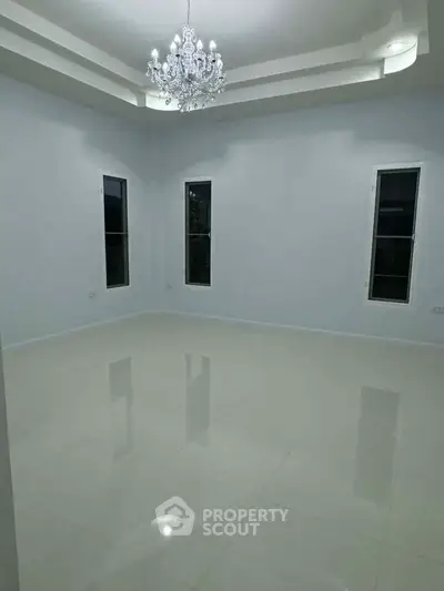 Spacious empty room with elegant chandelier and glossy tile flooring