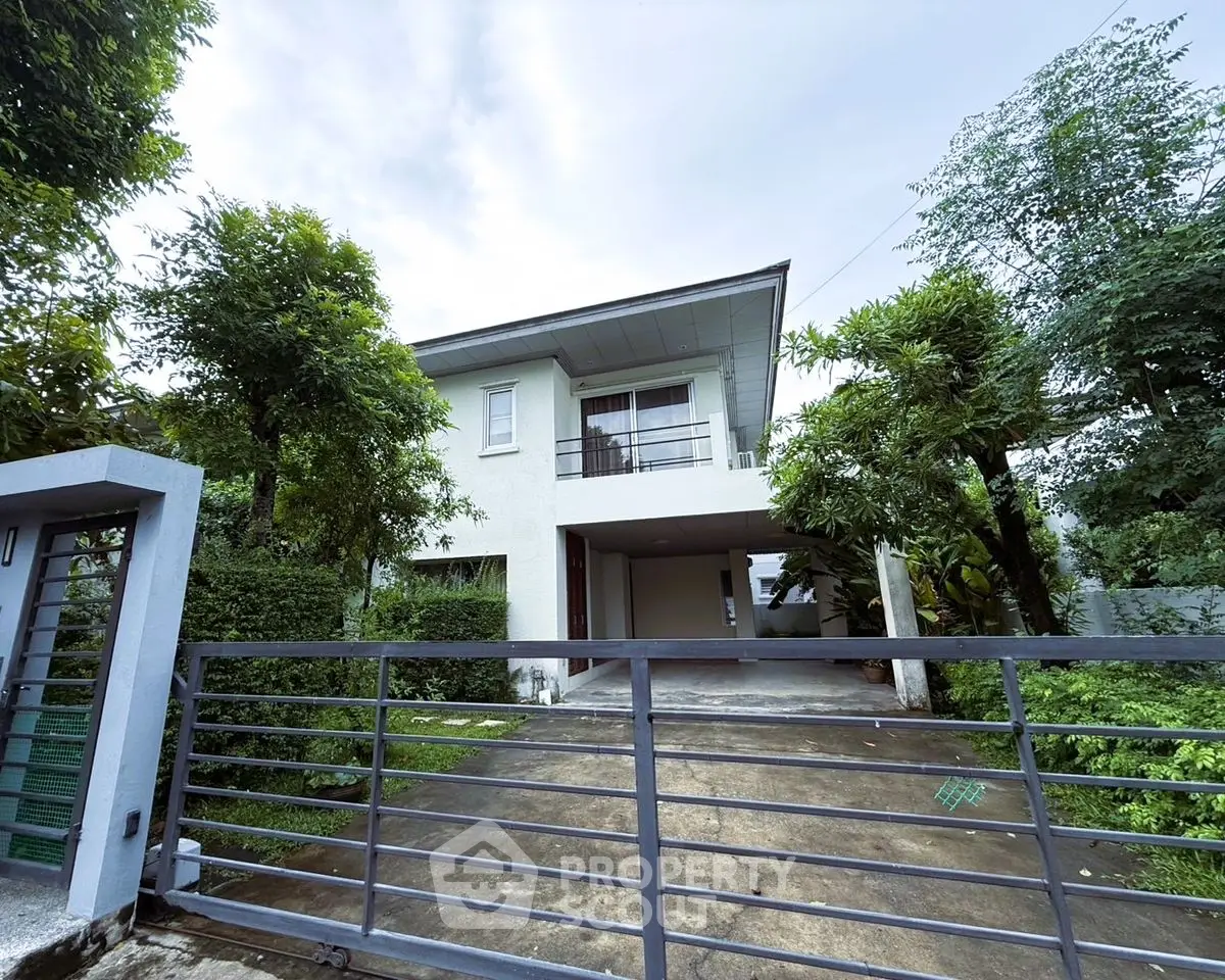 Charming two-story house with lush greenery and spacious driveway