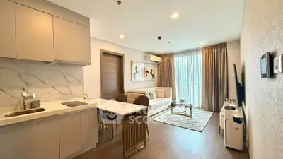Modern open-layout living room with kitchen, featuring elegant decor and natural light.