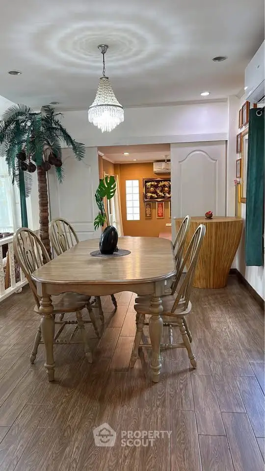 Charming dining area with wooden table, chairs, and elegant chandelier in cozy home setting.