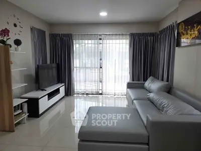 Modern living room with sleek gray sofa and large TV, featuring elegant curtains and glossy tiled floor.