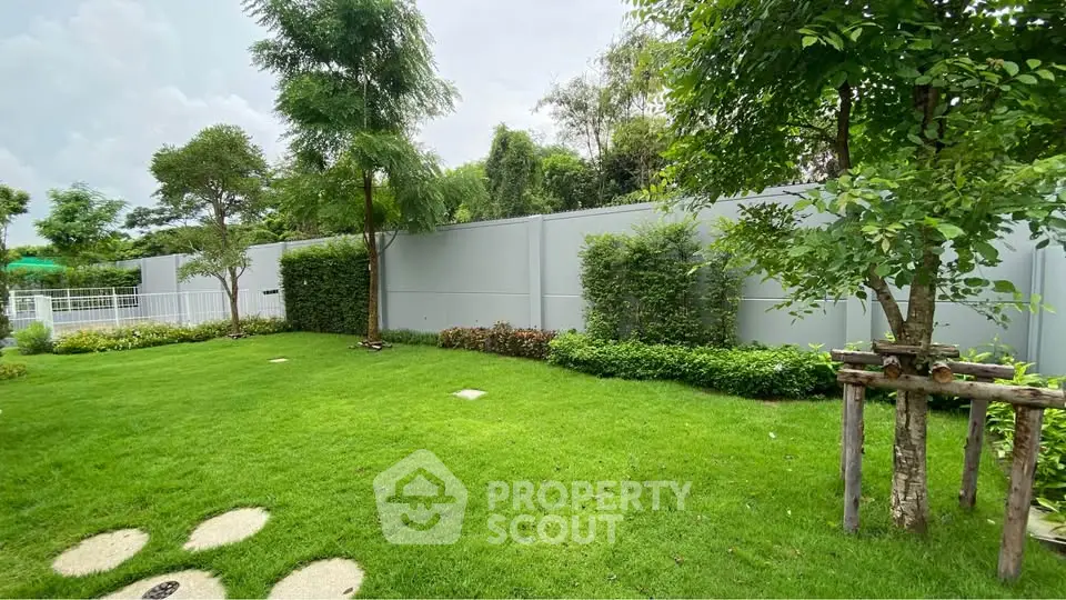 Lush green garden with manicured lawn and trees, perfect for outdoor relaxation.