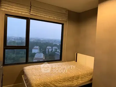 Cozy bedroom with large window offering a scenic view of the city skyline.