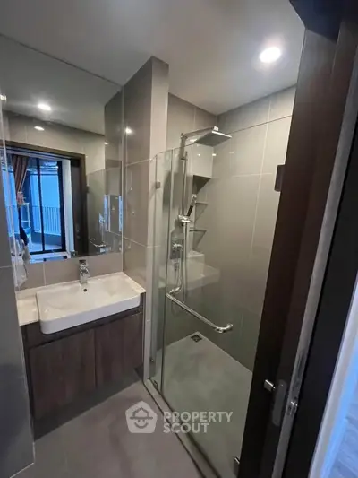 Modern bathroom with glass shower and sleek vanity in contemporary apartment.
