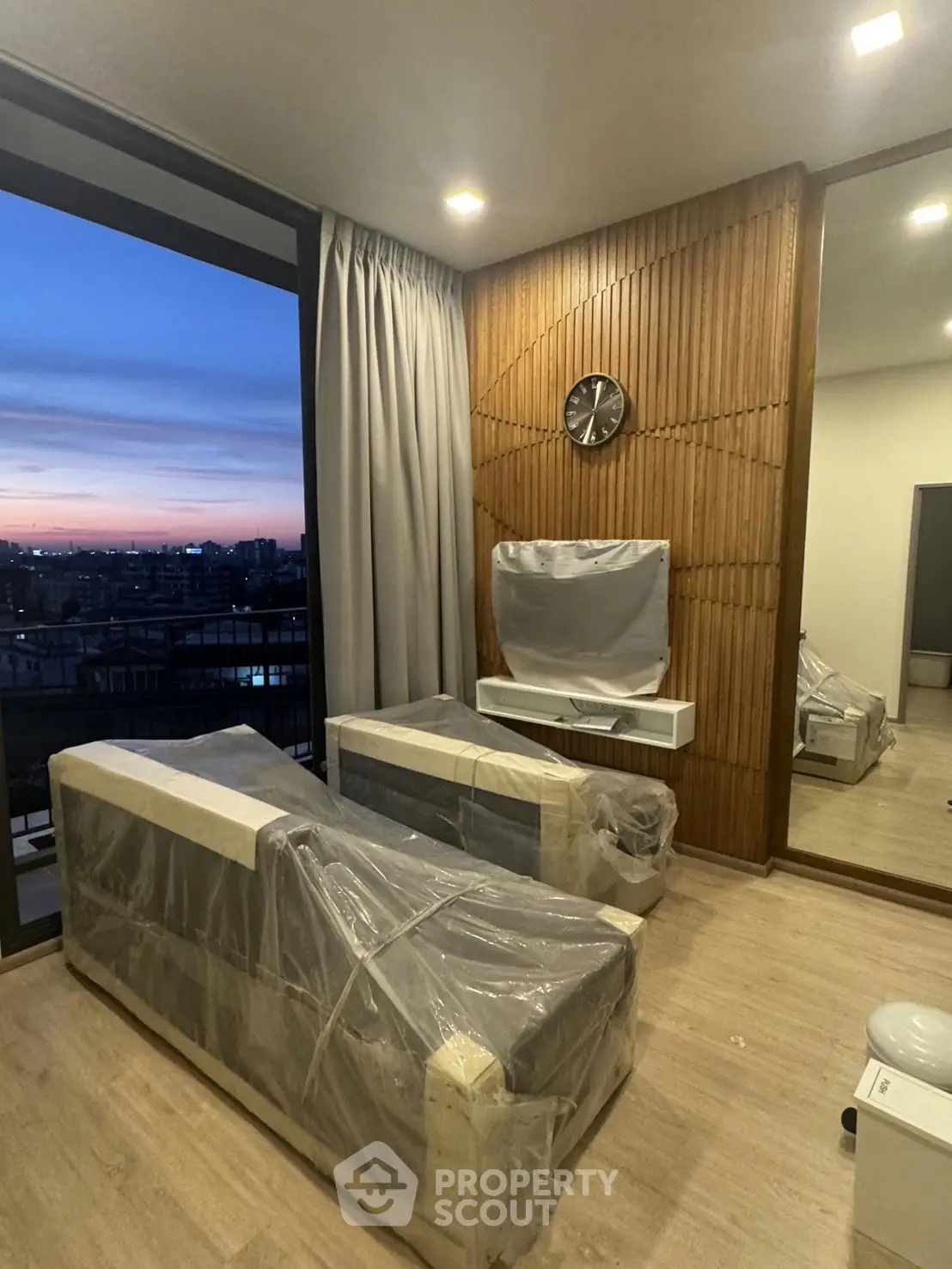 Modern living room with panoramic city view and stylish wooden wall paneling.
