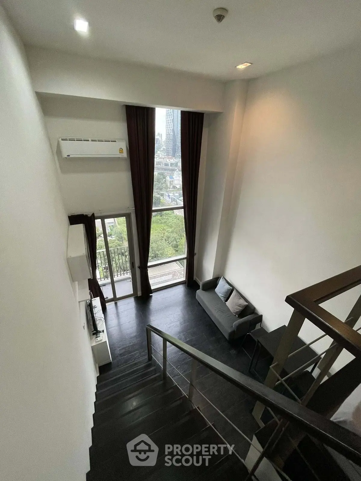 Stunning loft apartment with high ceilings and city view from the balcony, featuring modern interior design.