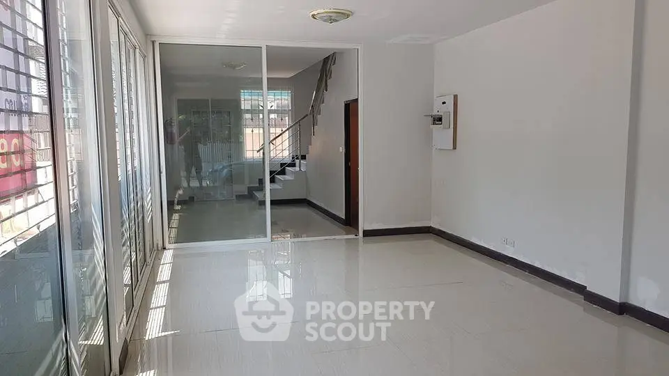 Spacious open-plan living area with large windows and modern staircase.