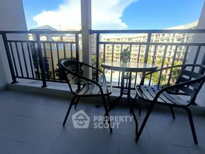Charming balcony with seating and scenic view of modern apartment complex.