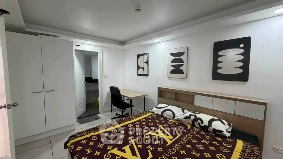 Modern bedroom with stylish decor and workspace, featuring sleek furniture and contemporary art.