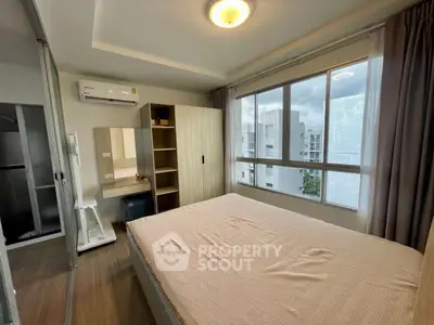Modern bedroom with large window and built-in wardrobe in urban apartment