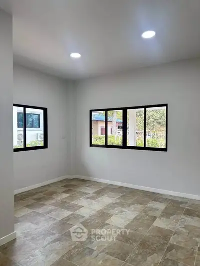 Spacious empty room with large windows and tiled flooring, perfect for customization.