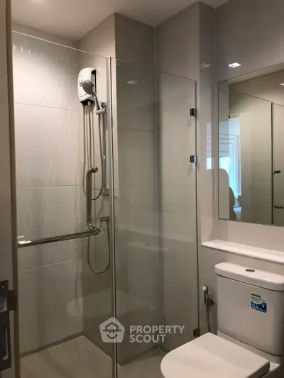 Modern bathroom with glass shower enclosure and sleek fixtures in a contemporary apartment.