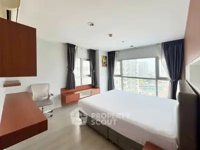 Spacious bedroom with city view, modern furnishings, and ample natural light in a high-rise apartment.