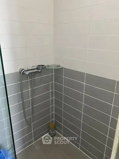 Modern bathroom with sleek gray and white tiles and a glass shower partition.