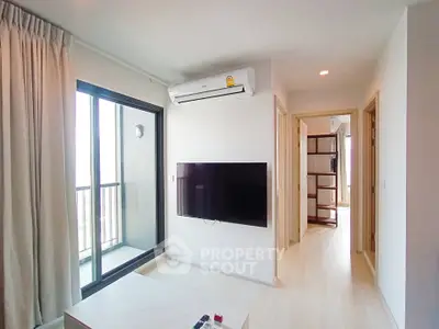 Modern living room with balcony access and wall-mounted TV in a stylish apartment.