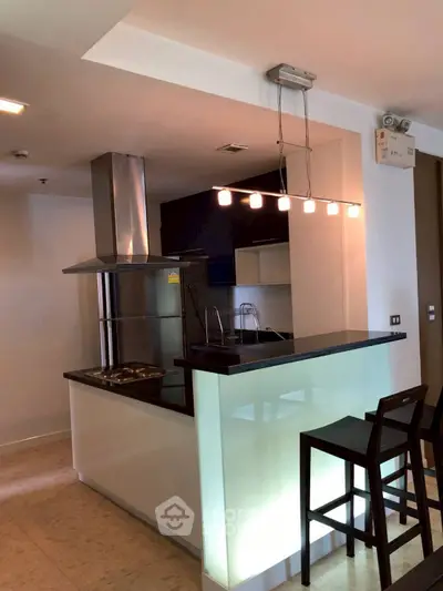 Modern kitchen with sleek breakfast bar and stylish lighting in a contemporary apartment.