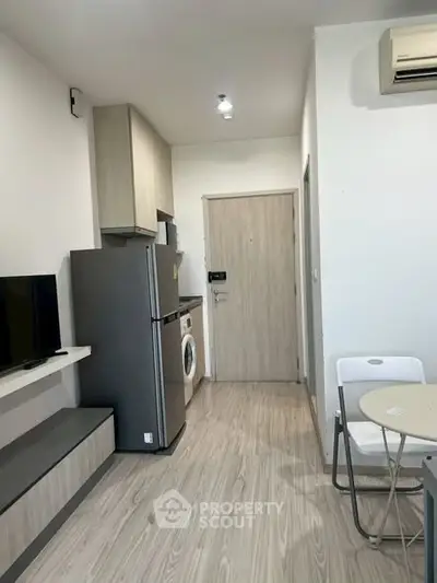 Modern compact apartment with integrated kitchen and living area, featuring sleek appliances and minimalist design.