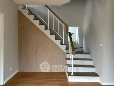 Modern staircase with wooden steps and built-in storage in a stylish home interior.