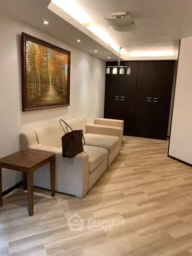 Elegant living room with modern lighting, sleek furniture, and a warm-toned hardwood floor, complemented by a tasteful art piece.